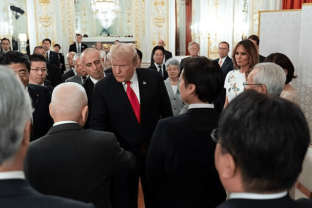 Trump in a crowded room surrounded by people.