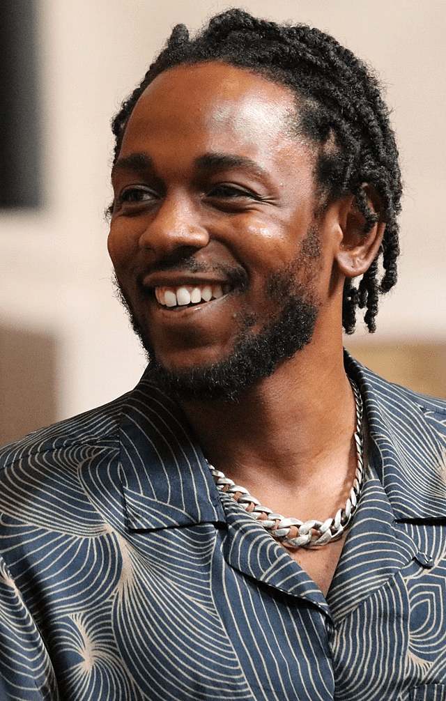 Kendrick Lamar with dreadlocks and black collared shirt.
