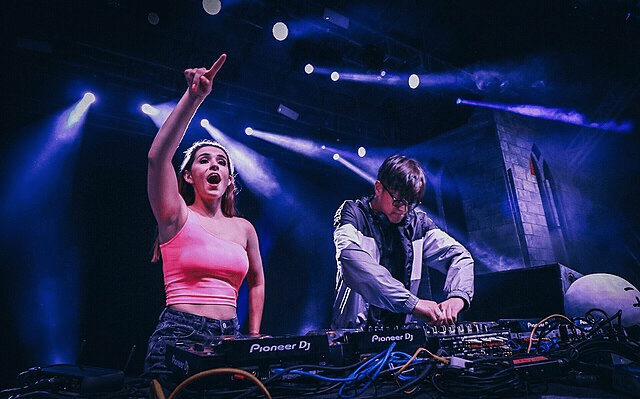 Two people standing behind dj station